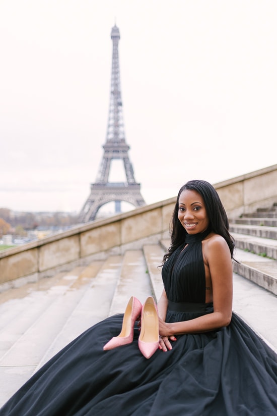 Beautiful black girl holding pink Louboutin high heels shoes in front of the Eiffel Tower in Paris Beautiful black girl holding pink Louboutin high heels shoes in front of the Eiffel Tower in Paris
