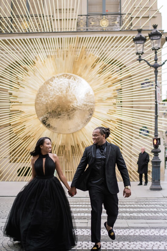 Couple photo shoot in Paris - Young couple running across the street in front of Louis Vuitton store in Place Vendome Couple photo shoot in Paris - Young couple running across the street in front of Louis Vuitton store in Place Vendome