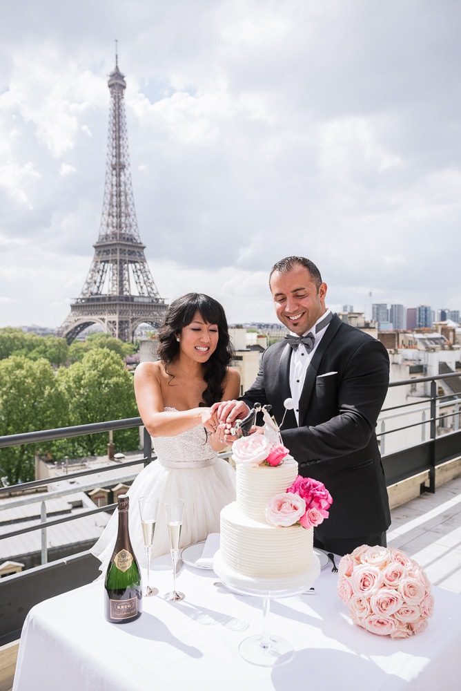 Paris elopement - Bride and groom cutting wedding cake on Shangri La terrace with Eiffel Tower in the background - Planned by Rendez-Vous in Paris Paris elopement - Bride and groom cutting wedding cake on Shangri La terrace with Eiffel Tower in the background - Planned by Rendez-Vous in Paris