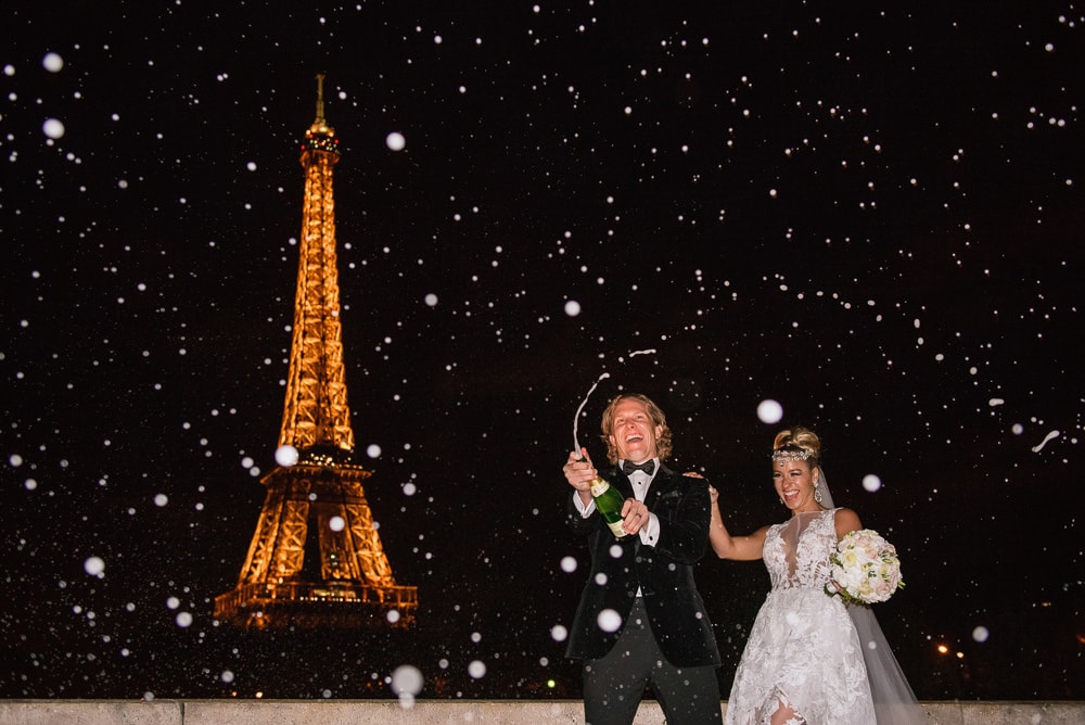 Paris elopement photographer - Bride and groom celebrate with champagne pop in front of the Eiffel Tower by night Paris elopement photographer - Bride and groom celebrate with champagne pop in front of the Eiffel Tower by night