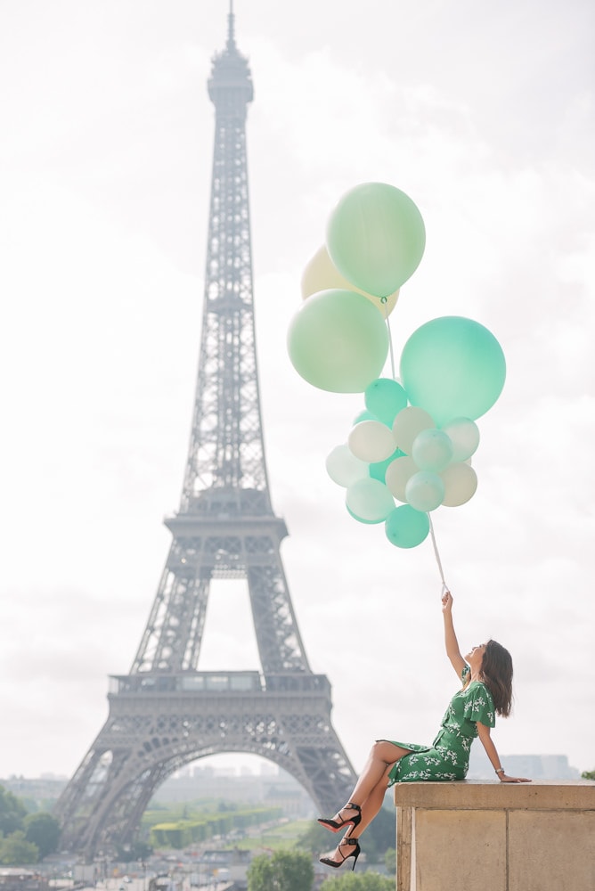Indonesian girl holding green balloons is posing in front of the Eiffel Tower during a mid day photo shoot with The Paris Photographer Indonesian girl holding green balloons is posing in front of the Eiffel Tower during a mid day photo shoot with The Paris Photographer
